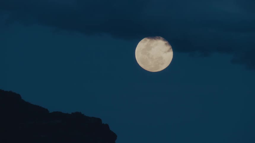 Clouds are above a full moon in the sky