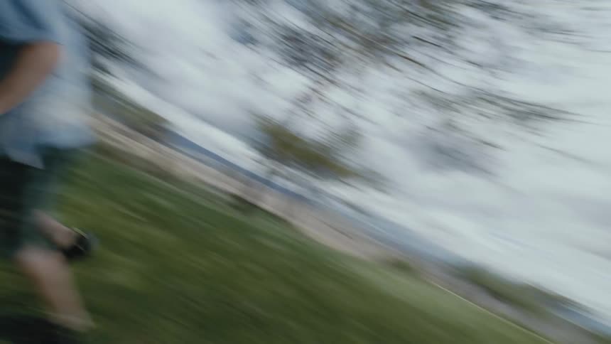 Boy and girl running around playing catch in a large grass field at a sunny day