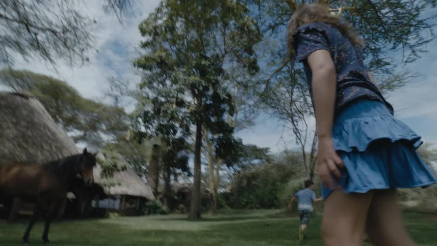 Two children run around the yard
