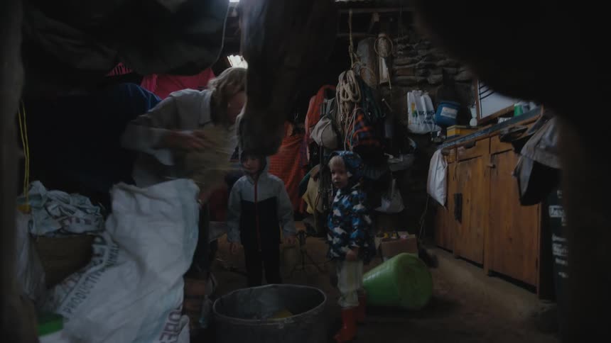 Mother and children filling a bowl with horse food inside a shack in the farm