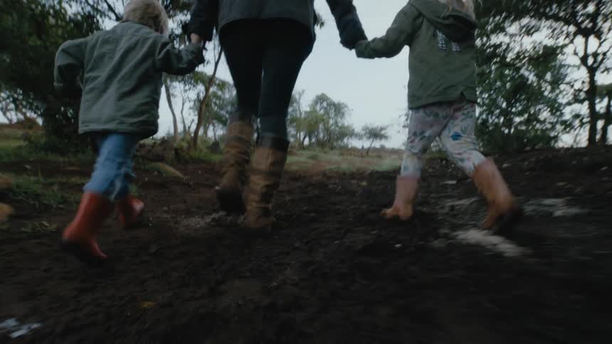 A mother is walking outdoors with her children