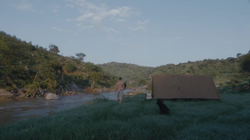 A man is walking outdoors near a tent