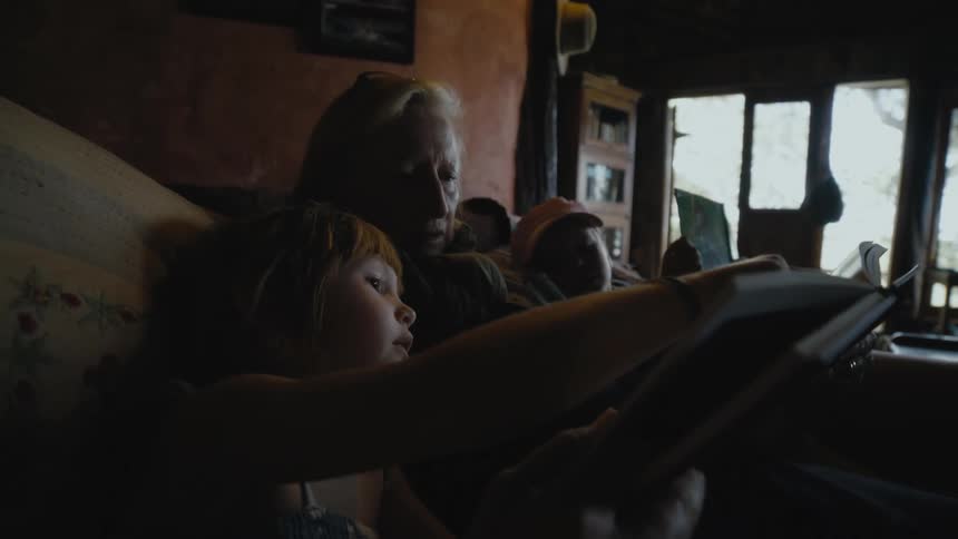 A woman reads to her grandkids on the couch