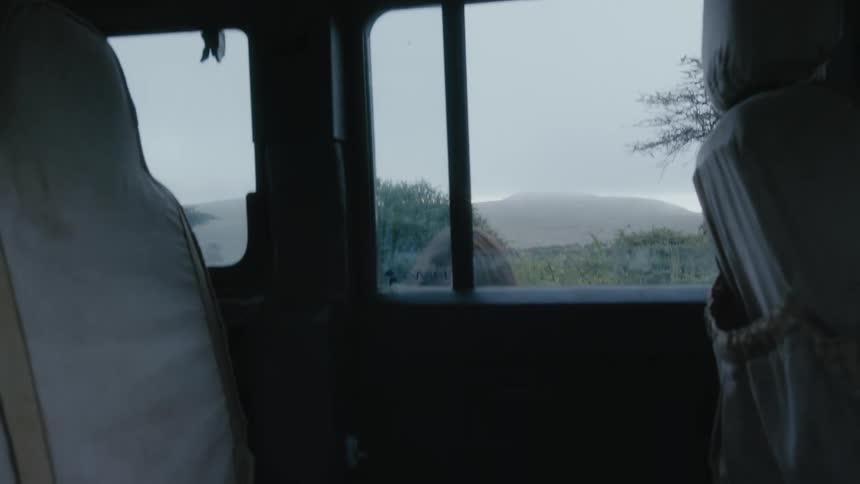 A child tosses her backpack through an open window before climbing into the backseat of a land rover