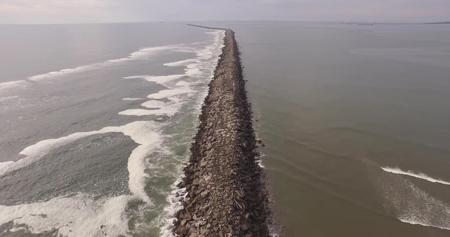 Aerial view of a long string of rocks in the water