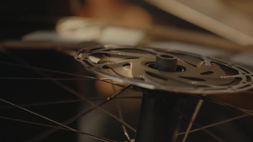A person repairing a bicycle tire tries a bolt cap on for size