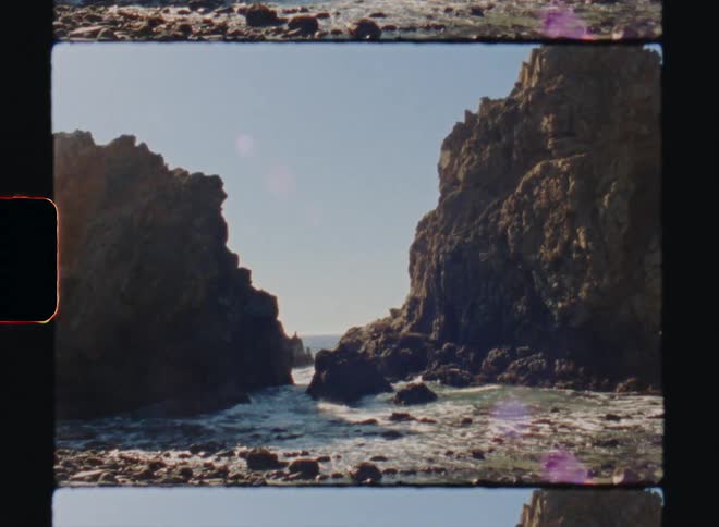 Ocean waves break against the shore with two steep cliffs Big Sur California Super 8 4k Film Scan