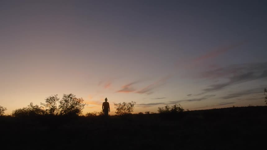 A person is walking outdoors while the sun is setting