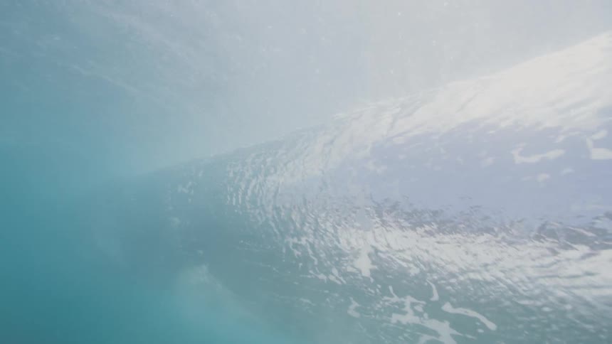 From beneath the ocean surface a powerful wave can be seen rolling and crashing onto itself