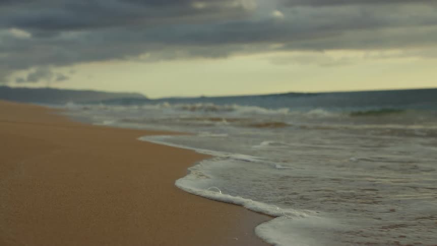 Ocean waves are moving towards the coast at dusk