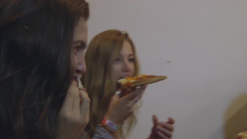 Group of young adults eating pizza while sitting in a booth