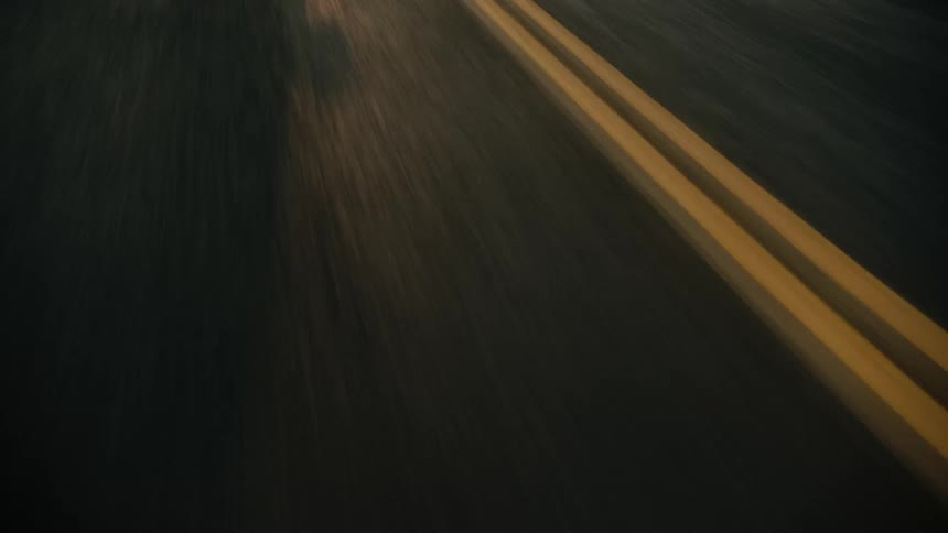 The shadow of a car traveling on a road with a double yellow line