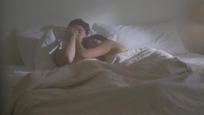 A couple hold each other in bed
