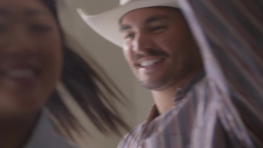 Woman holds single flower as couple smile and dance at home