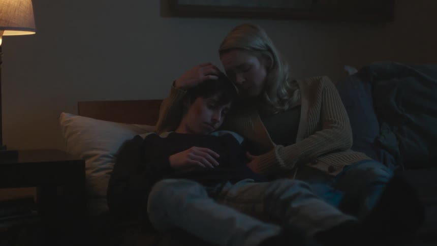 Mother lies on bed with bruised son comforting him