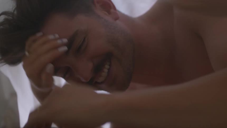 Man and woman make out in bed smiling
