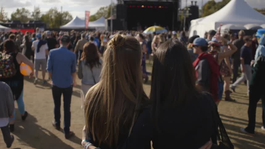 Two women embrace as they walk in a crowd of people