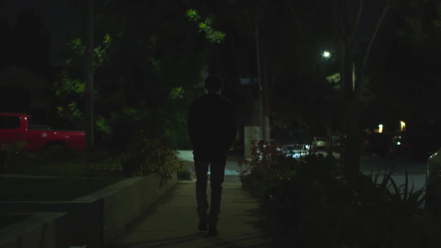 A person walking down a sidewalk at night