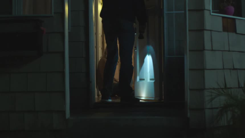 Worried woman scans outside hopefully as man returns with lit flashlight