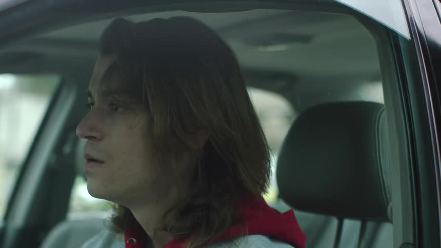 Man sitting in drivers seat sighs as he lays his head back against headrest