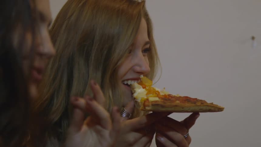 A woman takes a bite out of her pizza