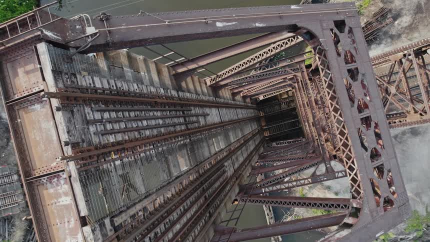 A raised drawbridge with train tracks with river water below