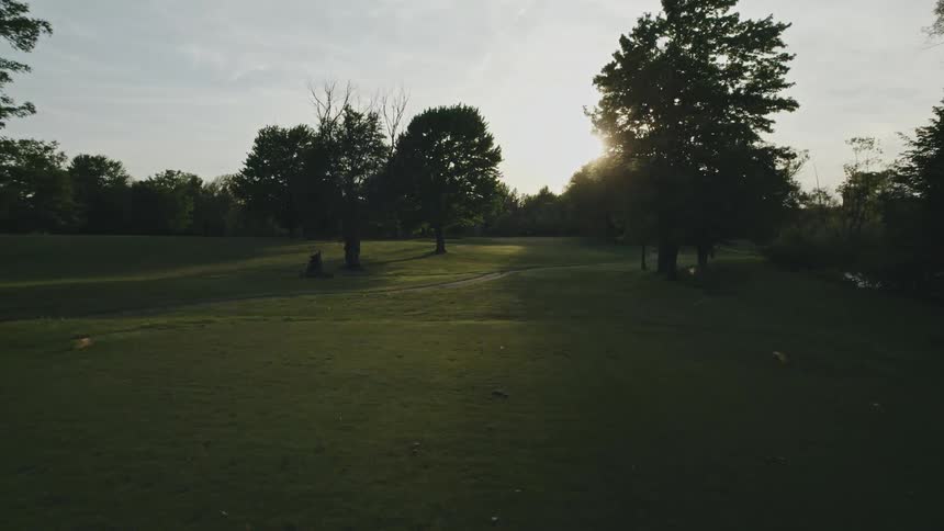A golfer swings and drives a ball down the course