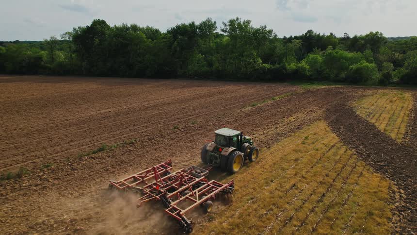 A tractor is moving on farm crops outdoors in spring