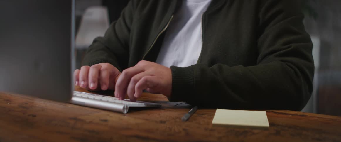 A man laughs to himself while typing on his desk