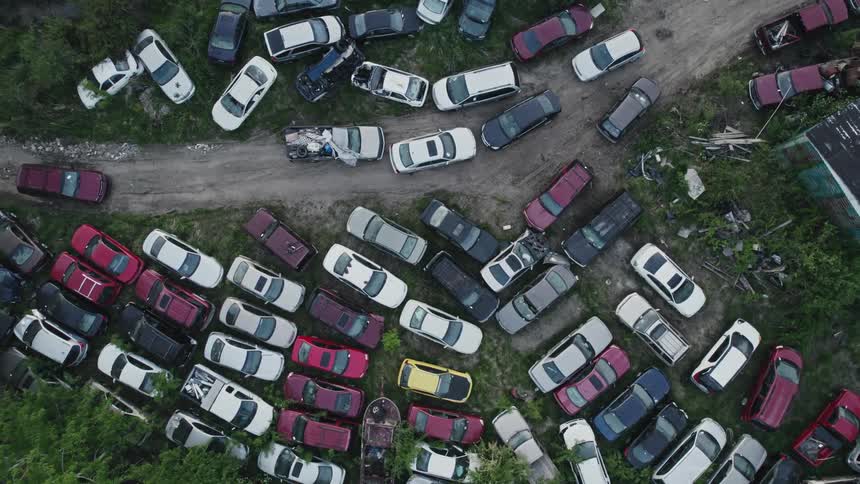 Vehicles in varying states of disrepair parked in and around a dirt road