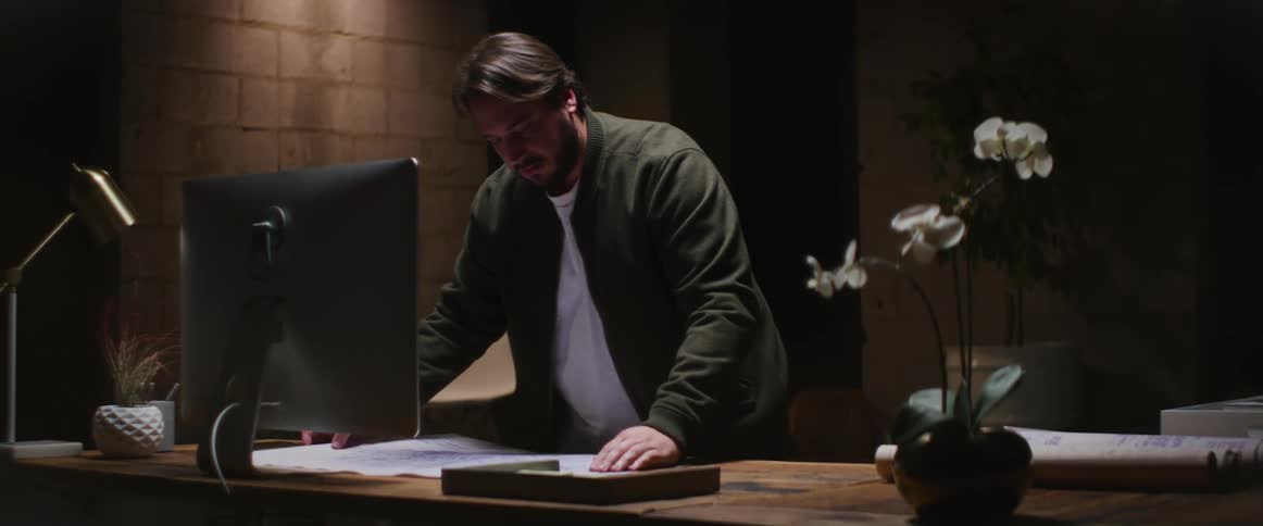 A man examines a blueprint while standing before a desk