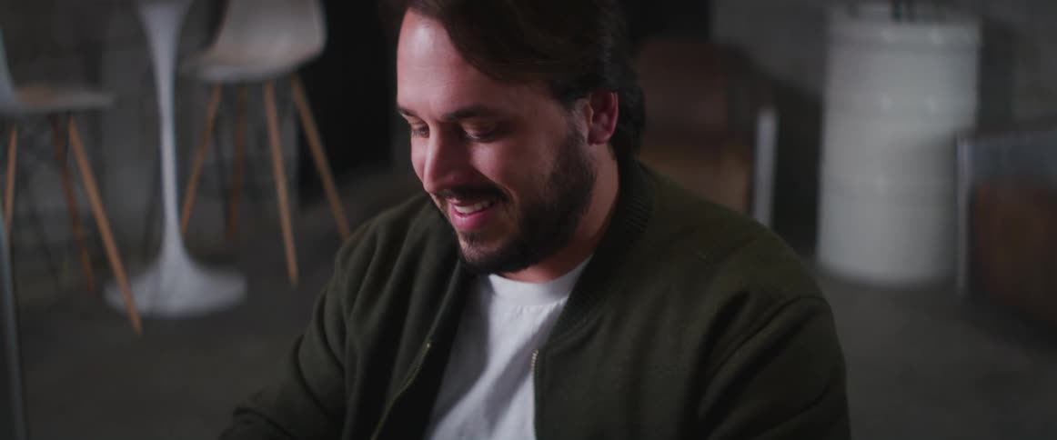 Man smiles while texting before returning to typing on computer