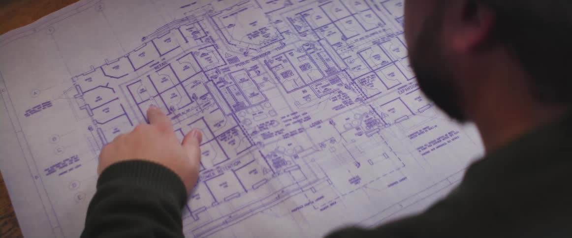 A man is pointing at the blueprints