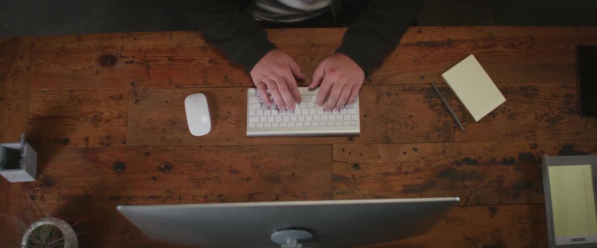 A person is sitting at a desk and typing on a computer