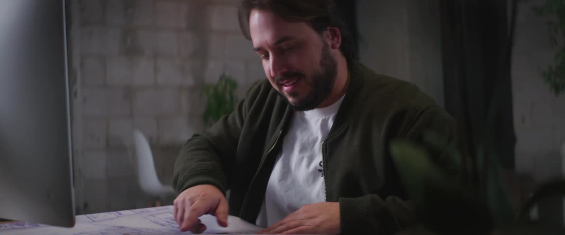 A man is smiling and sitting at a computer desk