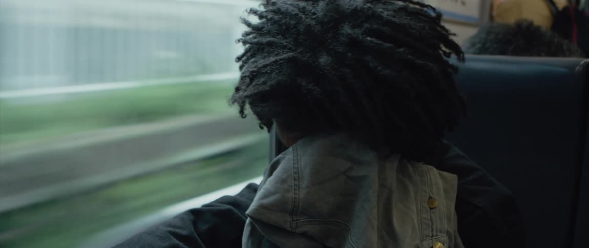 A passenger sitting on a traveling train covering their face with a jacket