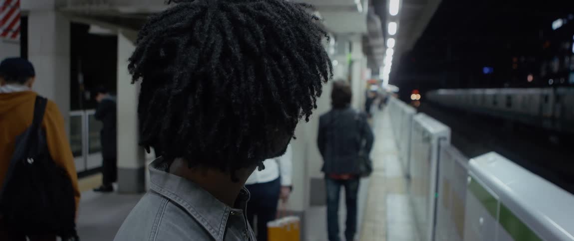 Man standing on a platform at a train station holds his arm up as a train goes by