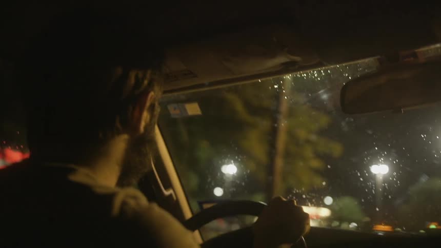 A man is driving a car at night