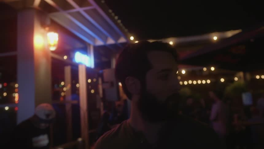 A man is walking past shops on a street at night