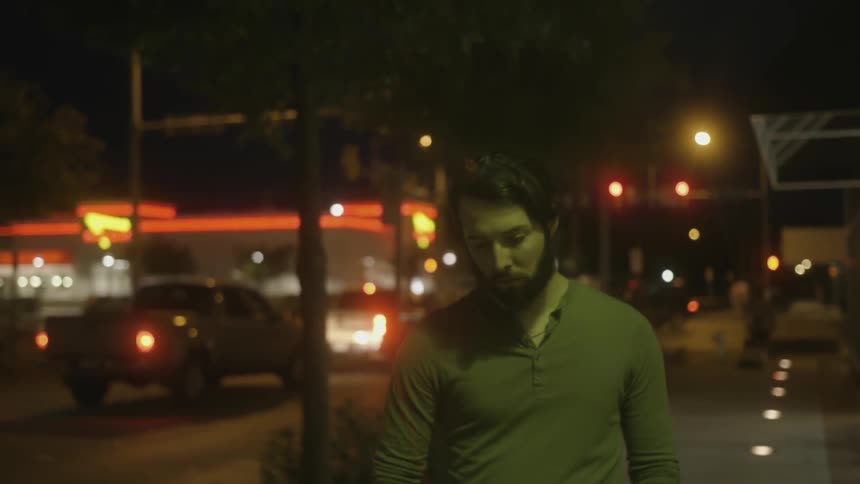 Man walks on a city sidewalk at night