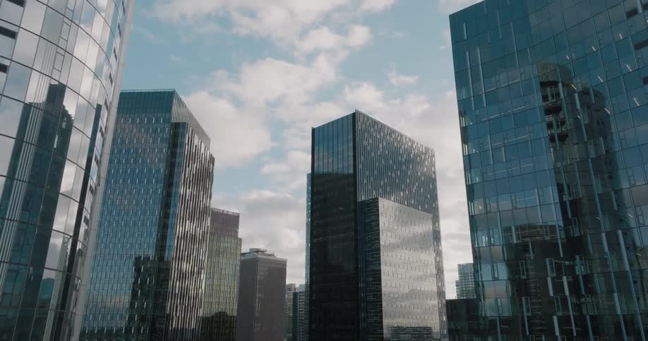 A cluster of reflective office towers shine under a beautiful sky