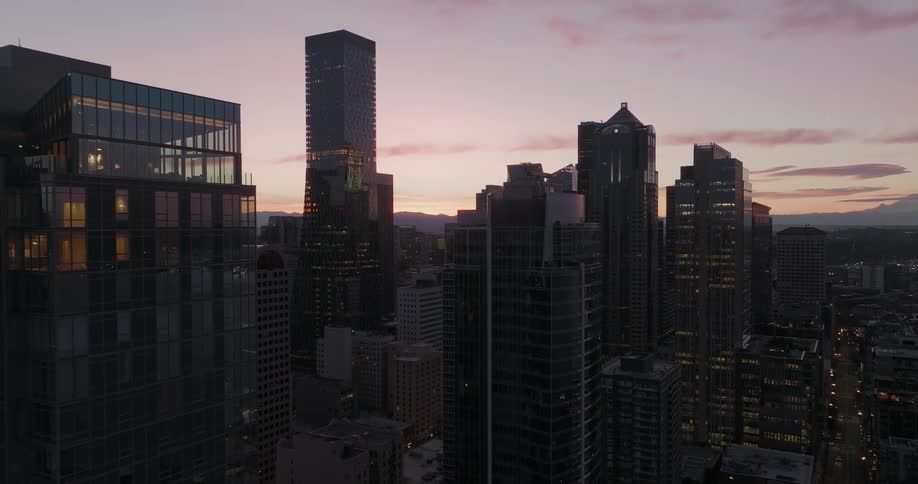 Pullback along the glass facade of an apartment tower at the first light of sunrise