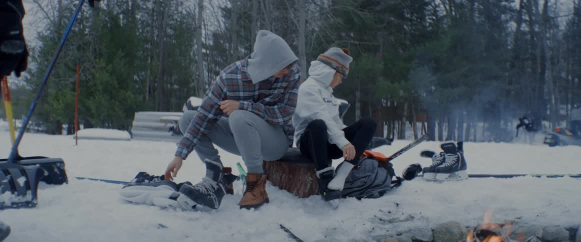 Teens sit next to a campfire on snow covered ground