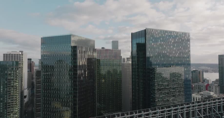 Ascending over gleaming office towers to reveal downtown skyscrapers in the distance