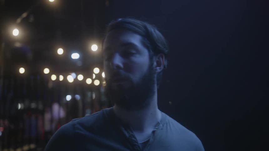 Man stands on a city sidewalk at night