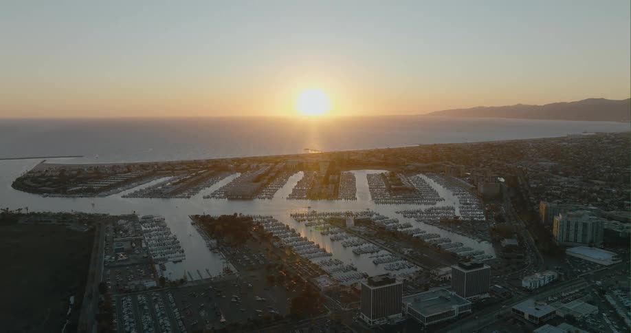 Dozens of boats sit in neat rows along the coast of a city