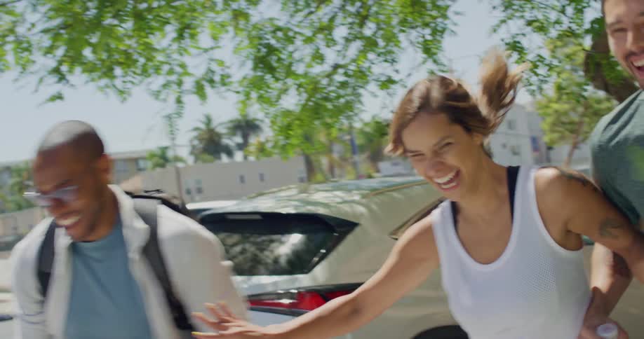Three friends on a sidewalk laugh as they begin to run racing each other
