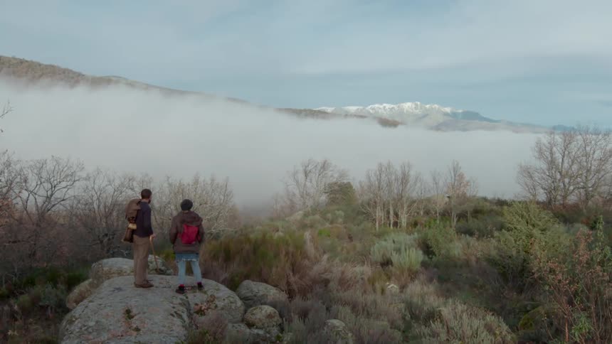 Two hikers enjoying a mountain view on a cloudy day