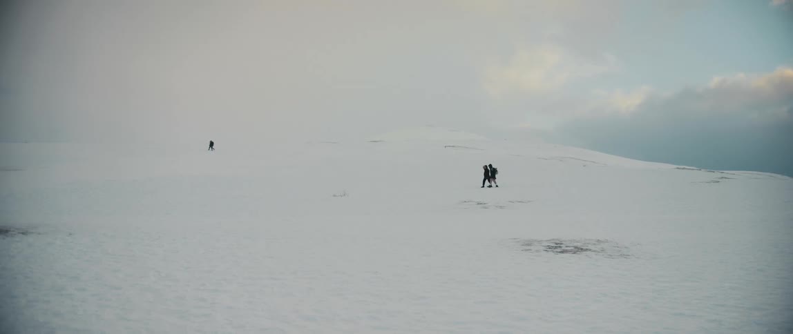 Two groups of two walk on a snow covered slope wearing backpacks