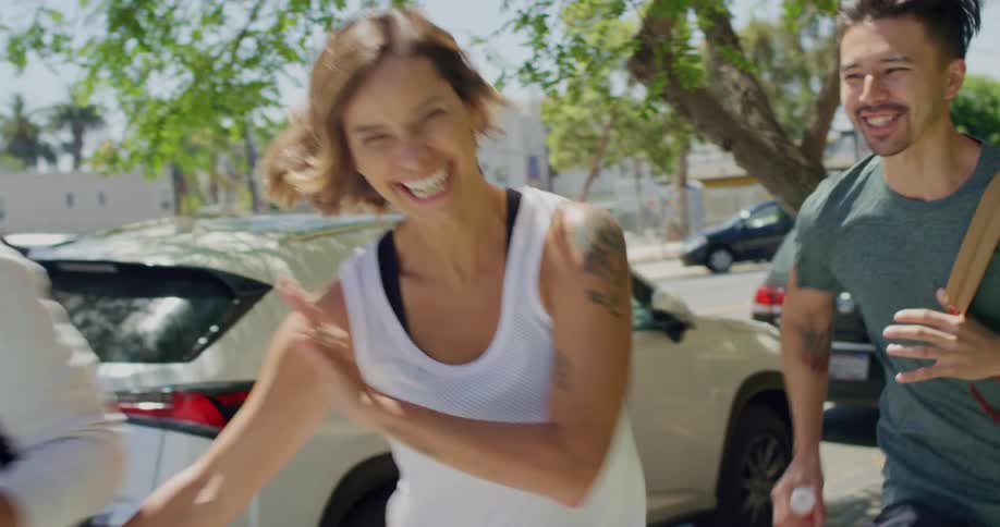 Smiling friends run down the sidewalk past cars